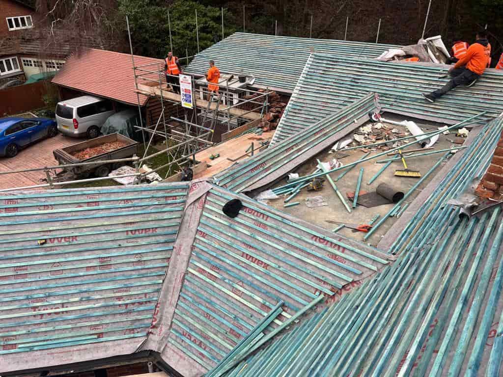 This is a photo of a large re-roof being carried out by PER Roofing Godmanchester, there are multiple sections of pitched roofs adjoining to a central flat roof